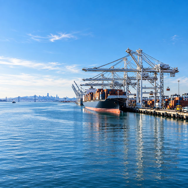 Container ship docked at the Port of Oakland under a clear sky